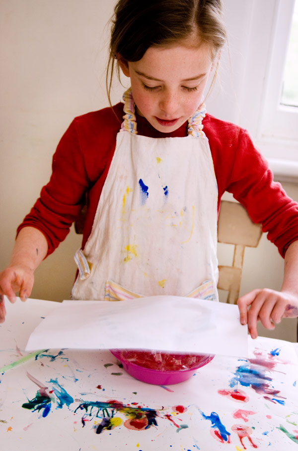 child placing paper on bowl of bubble paint