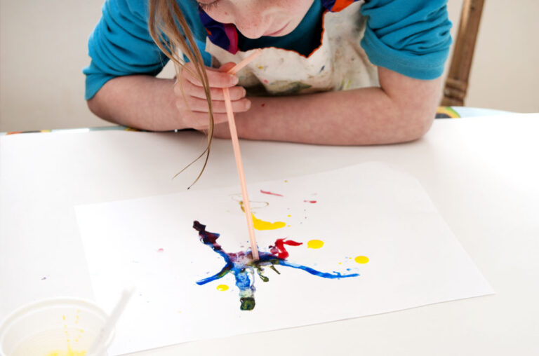 a child blowing paint with a straw