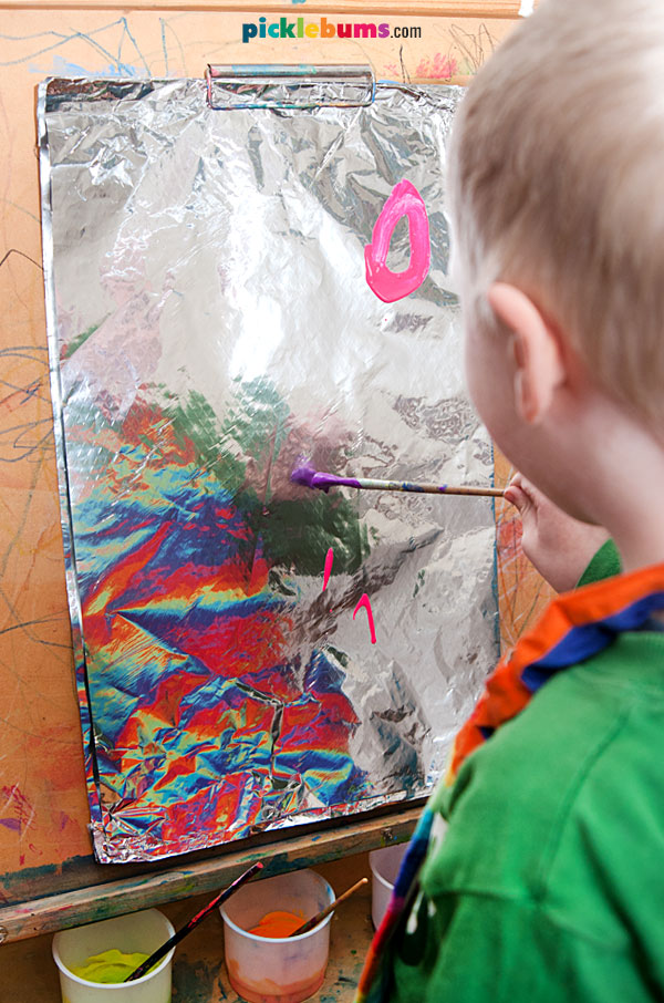 child painting on foil at easel