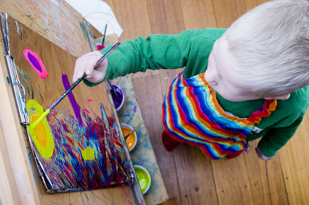 child painting on foil with brush