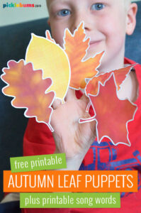 child holding paper autumn leaf puppets