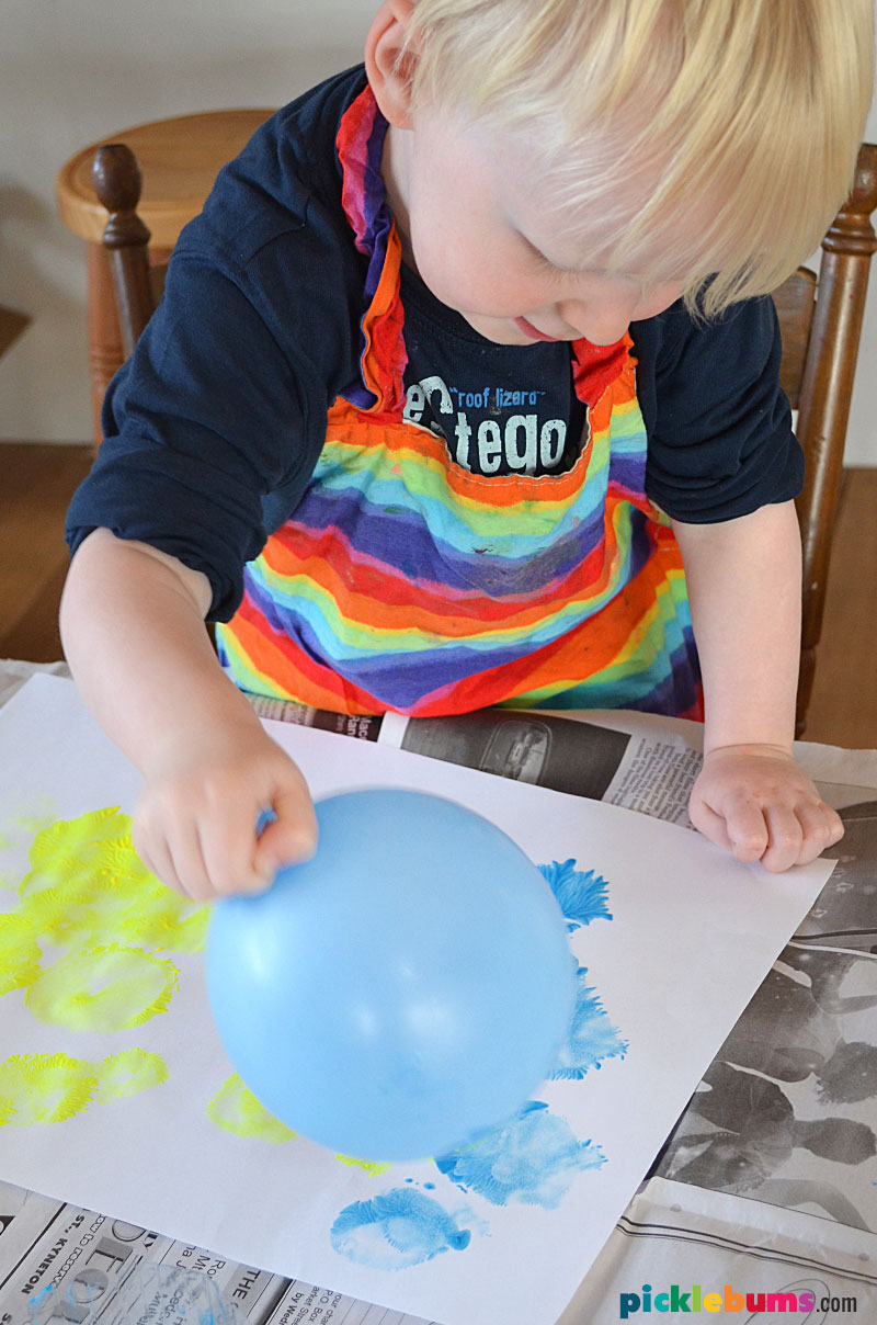 toddler painting with balloon on paper