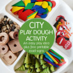 white plate with wooden shapes, road signs, and wooden trees for city playdough activity