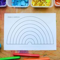 printable rainbow template surrounded by paints, playdough markers and collage materials
