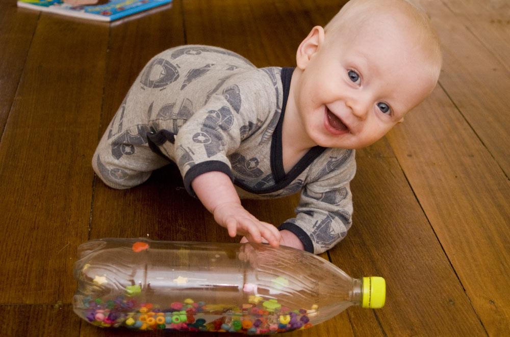 crawling baby playing with sensory bottle