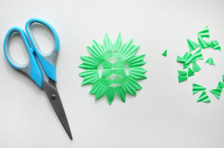 unfolding cupcake liner to show the paper snowflake